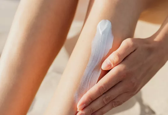 Una mujer aplicándose loción en la pierna